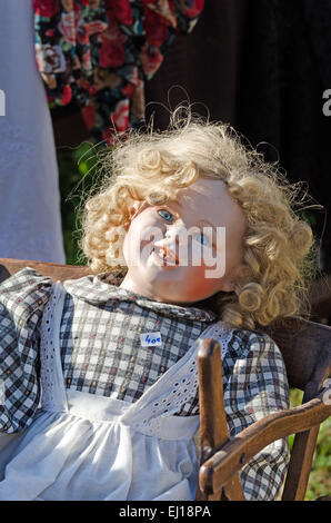 Eine alte Puppe sieht gruselig in der Morgensonne auf dem August-Flohmarkt in Gigny-Sûr-Saône, Burgund Frankreich Stockfoto