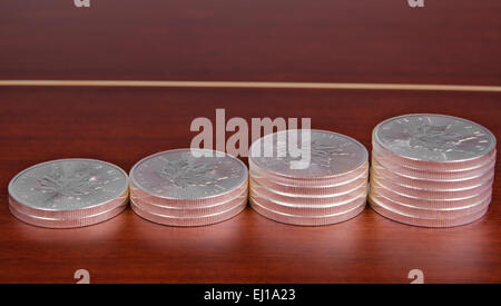 Silber Bullion Münze Investitionen, kanadische Maple Leaf auf Top Mahagoni Tisch gestapelt. Stockfoto