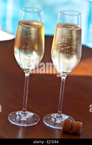 Champagner LUXUS URLAUB zwei frisch gegossene Gläser Sekt mit Kork auf der Terrasse Tisch Swimmingpool im Hintergrund Stockfoto