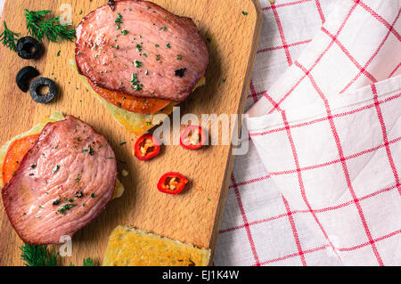 Gerösteten Toast Schinken und Tomate. Peperoni, Oliven und Gewürzen.  Anzeigen der Tischplatte Stockfoto