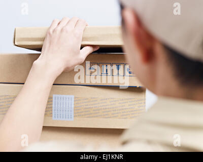 männliche asiatische Lieferbote Überprüfung Pakete geliefert werden. Stockfoto