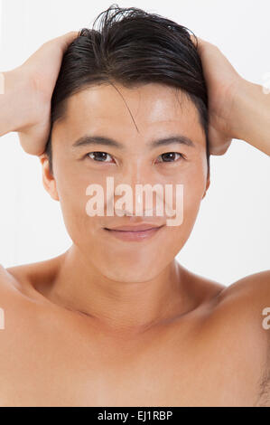Mann lächelnd in die Kamera mit den Händen in Haar Stockfoto