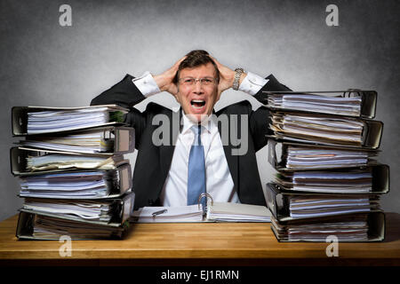 Überarbeitete weinende Geschäftsmann mit Menge von Dateien auf seinem Schreibtisch Stockfoto