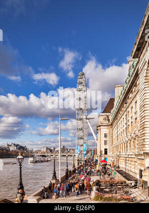 Blick entlang dem Südufer der Themse vor dem County Hall Gebäude gegenüber dem London Eye. Stockfoto