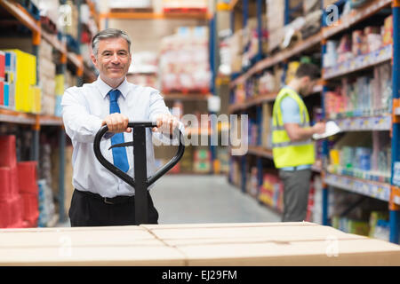 Manager ziehen Wagen mit Boxen an seine Mitarbeiter Stockfoto