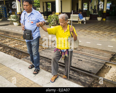 Ayutthaya, Ayutthaya, Thailand. 19. März 2015. Ein Taxifahrer hilft einen blinden Mann, die Plattform, um den Zug von Ayutthaya nach Bangkok. Die Bahnlinie von Bangkok nach Ayutthaya war die erste Eisenbahn in Thailand gebaut und wurde im Jahre 1892 eröffnet. Die staatliche Eisenbahn von Thailand (SRT), gegründet 1890, betreibt 4.043 Kilometer Meter Messgerät, das meisten Teilen von Thailand erreicht. Viel von der Strecke und viele der Züge sind in schlechtem Zustand und Züge fahren häufig spät. Unfälle und Pannen sind ebenfalls üblich. Aufeinanderfolgende Regierungen, einschließlich der aktuellen militärischen Regierung, haben Stockfoto