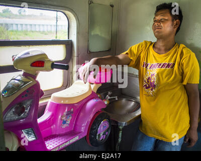 Ayutthaya, Ayutthaya, Thailand. 19. März 2015. Ein Personenzug tragen eine alte Arizona-Landesuniversität-t-Shirt auf die Ayutthaya, Bangkok dritter Klasse. Die Bahnlinie von Bangkok nach Ayutthaya war die erste Eisenbahn in Thailand gebaut und wurde im Jahre 1892 eröffnet. Die staatliche Eisenbahn von Thailand (SRT), gegründet 1890, betreibt 4.043 Kilometer Meter Messgerät, das meisten Teilen von Thailand erreicht. Viel von der Strecke und viele der Züge sind in schlechtem Zustand und Züge fahren häufig spät. Unfälle und Pannen sind ebenfalls üblich. Aufeinanderfolgende Regierungen, einschließlich der aktuellen militärischen go Stockfoto