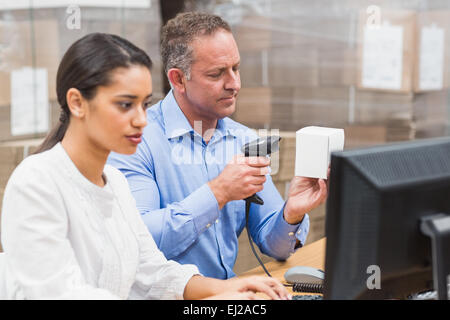 Manager, die Scan-Feld während sein Kollege auf Laptop tippen Stockfoto