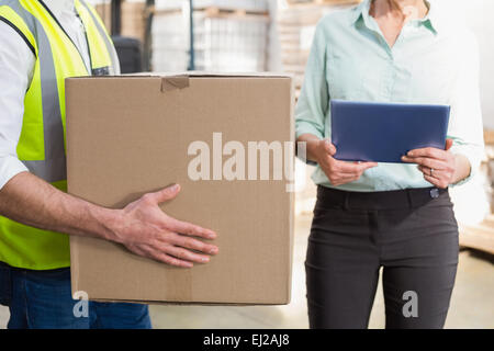 Arbeiter tragen Kasten mit Manager hält TabletPC Stockfoto