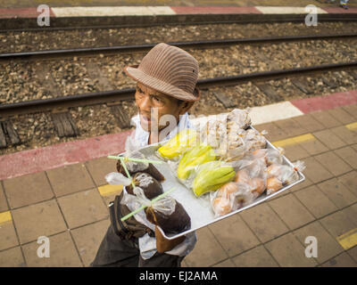 Prachinburi, Prachinburi, Thailand. 20. März 2015. Ein Verkäufer verkauft Obst auf einer Plattform in Prachinburi Bahnhof entfernt. Er verkaufte Snacks für Passagiere Reiten eines 3. Klasse-Zuges nach Kabin Buri. Die staatliche Eisenbahn von Thailand (SRT), gegründet 1890, betreibt 4.043 Kilometer Meter Messgerät, das meisten Teilen von Thailand erreicht. Viel von der Strecke und viele der Züge sind in schlechtem Zustand und Züge fahren häufig spät. Unfälle und Pannen sind ebenfalls üblich. Aufeinanderfolgende Regierungen, einschließlich der aktuellen militärischen Regierung haben versprochen, Bahnverkehr zu aktualisieren. Das Militär Stockfoto