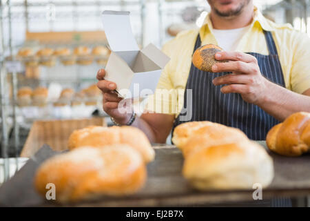 Arbeiter in Schürze holding Box und Brot Stockfoto