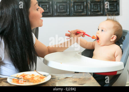 Mutter, die hungrigen sechs Monate altes Baby feste Nahrung Stockfoto