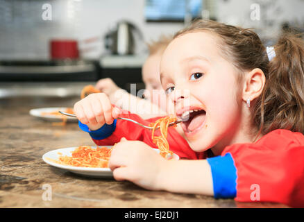 Kleine Mädchen essen Nudeln in der Küche-Tabelle Stockfoto