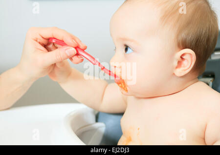 Mutter, die hungrigen sechs Monate altes Baby feste Nahrung Stockfoto