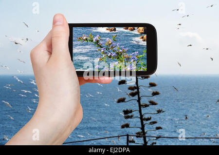 Konzept - Reisen Tourist nimmt Bild der Mittelmeer Küste in Costa Brava Küste auf Smartphone, Spanien Stockfoto