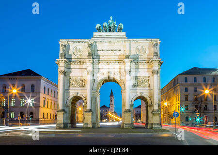 Das Siegestor (Englisch: Triumphbogen) in München. Dies ist eine lange Belichtung in der Abenddämmerung mit Datenverkehr rund um den Bogen Stockfoto