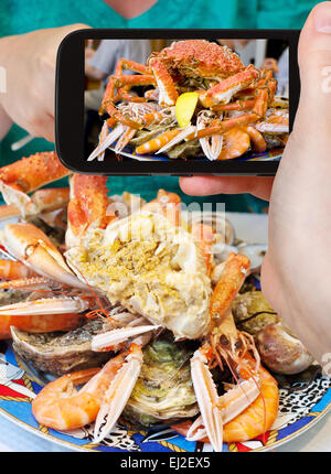 Fotografieren Food-Konzept - Tourist nimmt Bild der Meeresfrüchte-Platte mit Krabben, Garnelen, Garnelen auf Smartphone, Frankreich Stockfoto