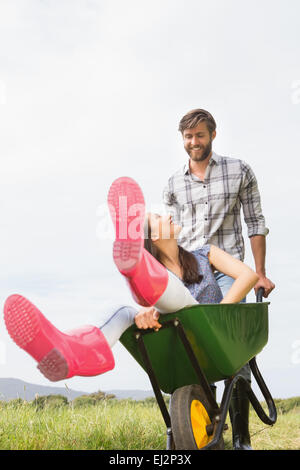 Mann seine Freundin in einer Schubkarre schieben Stockfoto