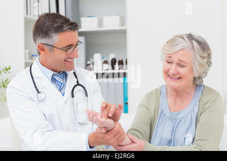 Männlichen Arzt untersuchen Patienten Hand am Tisch Stockfoto