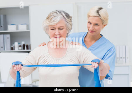 Krankenschwester Mitarbeitende senior Frau bei der Ausübung der mit Widerstand band Stockfoto