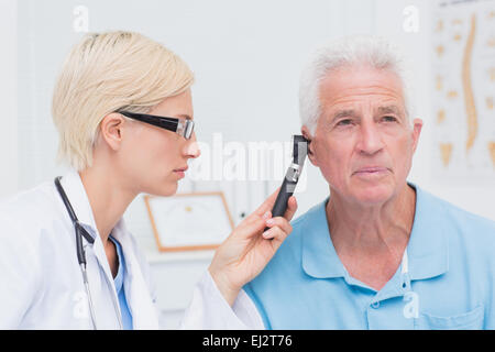 Arzt untersucht männlichen Patienten Ohr mit Otoskop Stockfoto