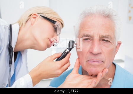 Arzt untersucht senior Patienten Ohr mit Otoskop Stockfoto
