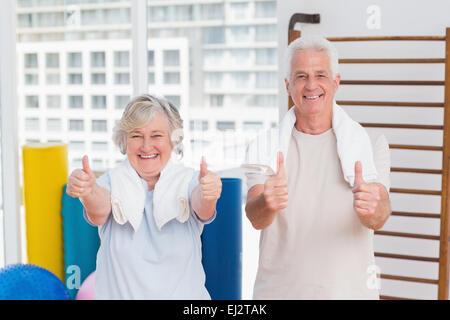 Älteres paar gestikulieren Daumen oben im Fitness-Studio Stockfoto