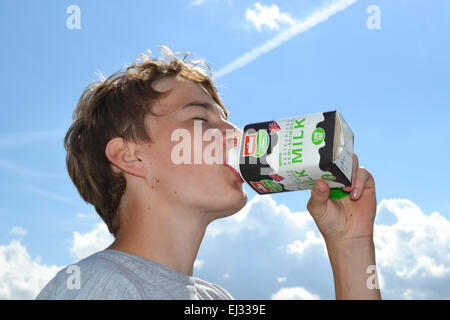 kleiner Junge aus einer Milchtüte im Sommer trinken Stockfoto