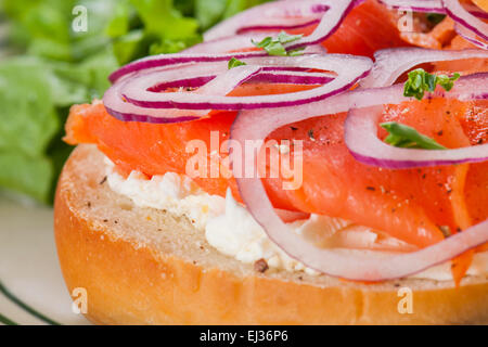 Bagel mit geräucherter Lachs Räucherlachs, Frischkäse und roten Zwiebeln, dazu Salat Salat. Stockfoto