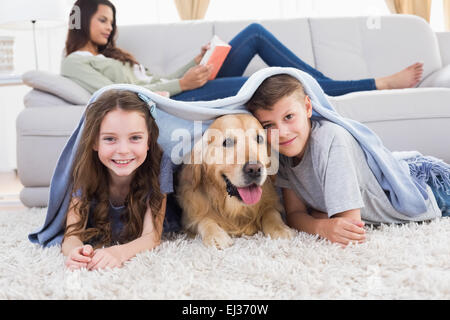 Glücklich Geschwister mit Hund unter Decke Stockfoto