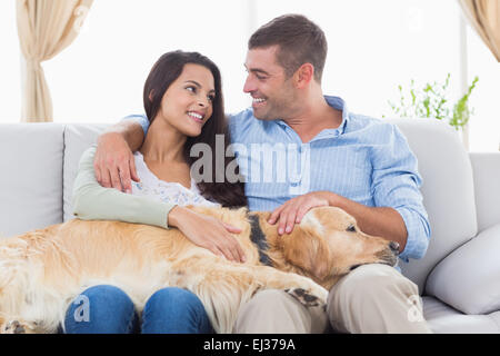 Glückliches Paar streicheln Golden Retriever auf sofa Stockfoto