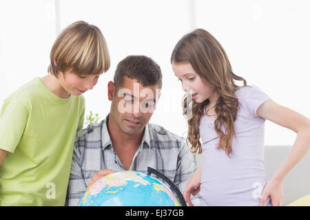 Geschwister mit Vater auf Globus Karte erkunden Stockfoto