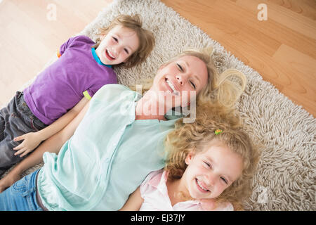 Glückliche Mutter und Kinder liegen auf Teppich Stockfoto