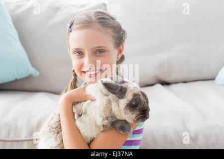 Glückliches Mädchen halten Kaninchen im Wohnzimmer Stockfoto