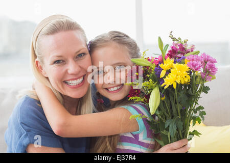 Mutter mit Blumenstrauß Umarmung Tochter im Haus Stockfoto