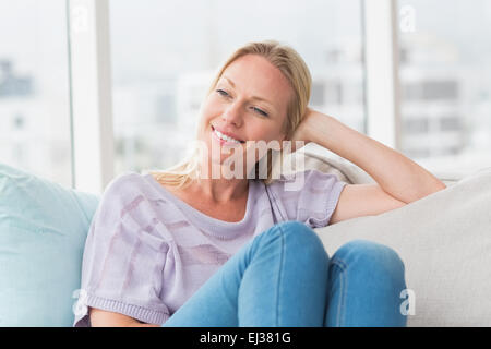 Entspannte Frau wegsehen sitzend auf sofa Stockfoto