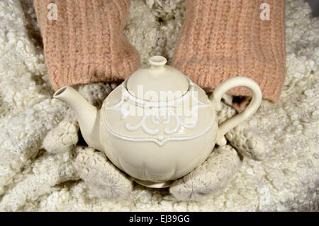 Hände in Handschuhe halten Teekanne Stockfoto