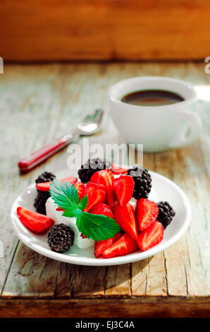 Fettarmer Sahne-Käse mit Brombeeren und Erdbeeren, Kaffee serviert auf einem Vintage Holztisch Stockfoto