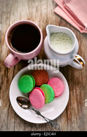 Decafeinated Kaffee, Milch und Makronen (Mandel Sandwich Cookies) auf dem Vintage Holztisch Stockfoto