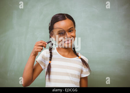 Kleines Mädchen hält Lupe im Klassenzimmer Stockfoto