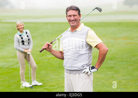 Glücklich Golfer mit Partner hinter ihm Abschlag Stockfoto