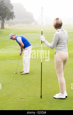 Lady Golfer mit Fahne für Partner setzen Kugel Stockfoto