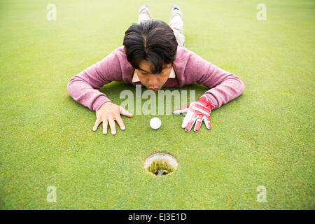 Golfer, die versuchen, den Ball ins Loch zu schlagen Stockfoto