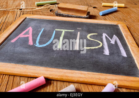 der Wort Autismus mit Kreide in verschiedenen Farben in einer Tafel geschrieben auf einem rustikalen hölzernen Pult oder Tisch platziert Stockfoto