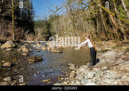 Neun Jahre altes Mädchen und sieben Jahre alten Jungen werfen von Steinen in den Snoqualmie River in der Nähe von North Bend, Washington, USA Stockfoto