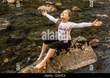 Neun Jahre altes Mädchen mit Begeisterung und Freude warf ihre Arme breit, in Snoqualmie River in North Bend, Washington Stockfoto