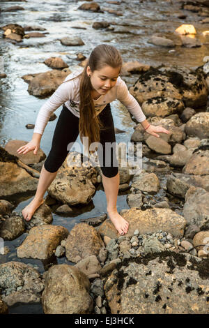 Neunjähriges Mädchen Klettern auf Felsen in Snoqualmie River, in der Nähe von North Bend, Washington, USA Stockfoto