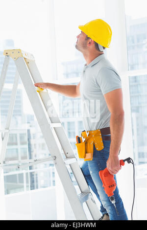 Handwerker mit Bohrer Maschine klettern Leiter im Gebäude Stockfoto
