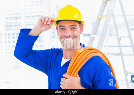 Zuversichtlich Handwerker tragen Schutzhelm Draht Roll mit gedrückter Stockfoto