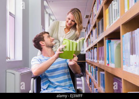 Lächelnd behinderte Schüler mit Klassenkameraden in Bibliothek Stockfoto